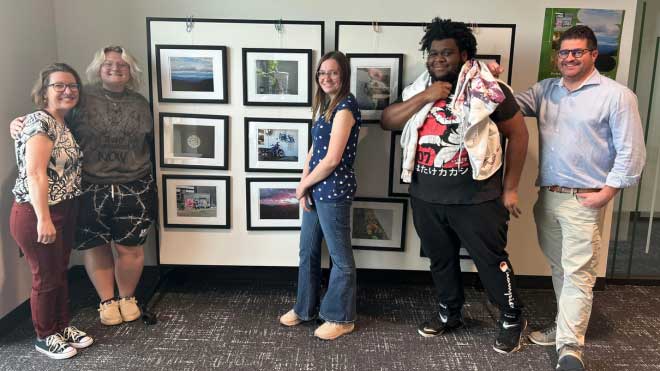 Stephanie Danker, Mel Hale, Emma Personette, Myles Harrison, and Brian Schultz stand together in front of student photography from the Pura Vida: Education and Community in Costa Rica exhibit at Miami University.