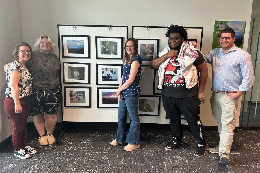 Stephanie Danker, Mel Hale, Emma Personette, Myles Harrison, and Brian Schultz stand together in front of student photography from the Pura Vida: Education and Community in Costa Rica exhibit at Miami University.