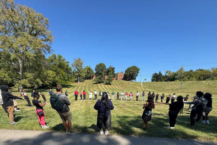 TEACh Cincinnati students and Miami University facilitators form a large outdoor circle at Peffer Park for a ropes course activity.