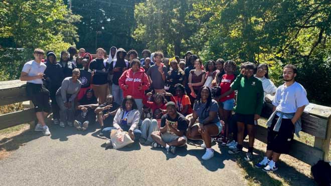 Large group of Miami University TEACh Cincinnati students and mentors pose on a bridge during a ropes course event in Peffer Park.