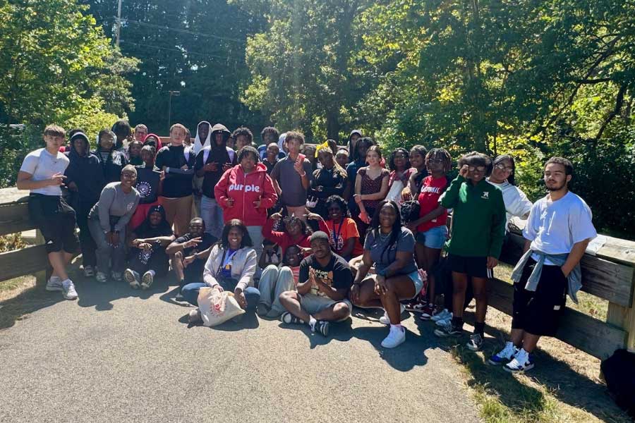 Large group of Miami University TEACh Cincinnati students and mentors pose on a bridge during a ropes course event in Peffer Park.