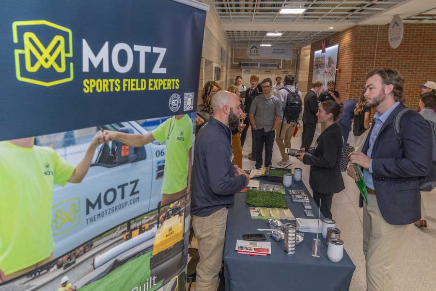 Attendees at SCENE talk with a Motz representative about sports field careers at Miami University’s networking expo.