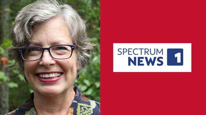 Kathleen Knight Abowitz smiling outdoors next to Spectrum News 1 logo on red background.