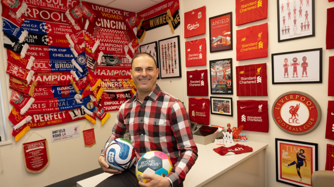 Adam Beissel holding soccer balls in his office