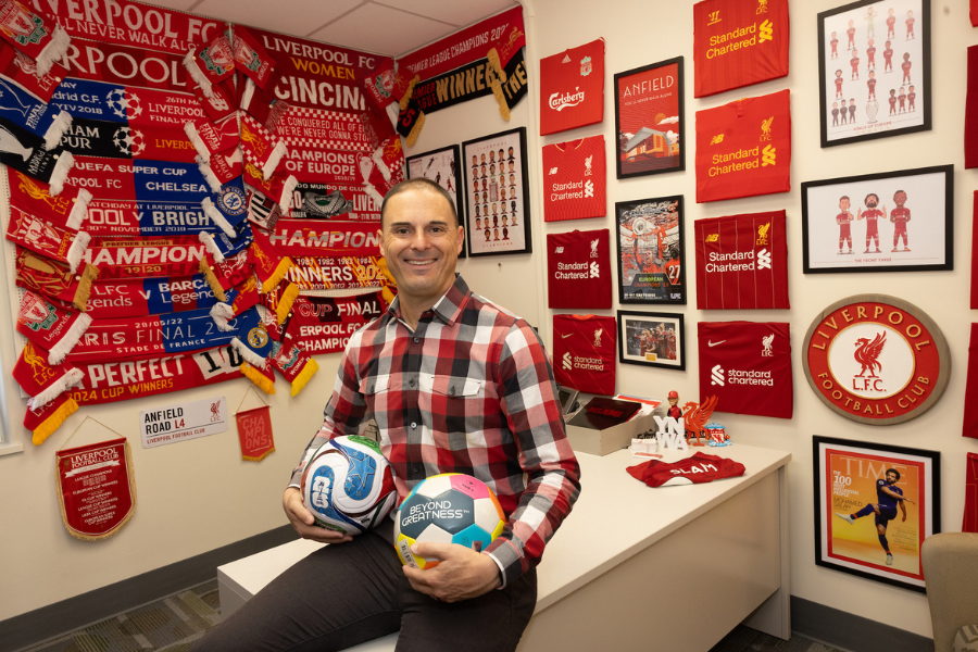 Adam Beissel holding soccer balls in his office