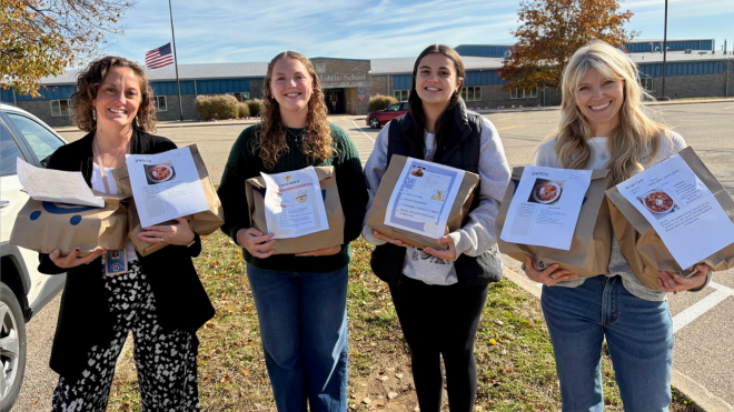 Four females holding food bags in front of Talawanda Middle School