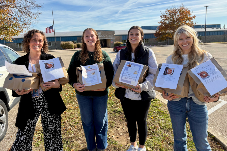 Four females holding food bags in front of Talawanda Middle School