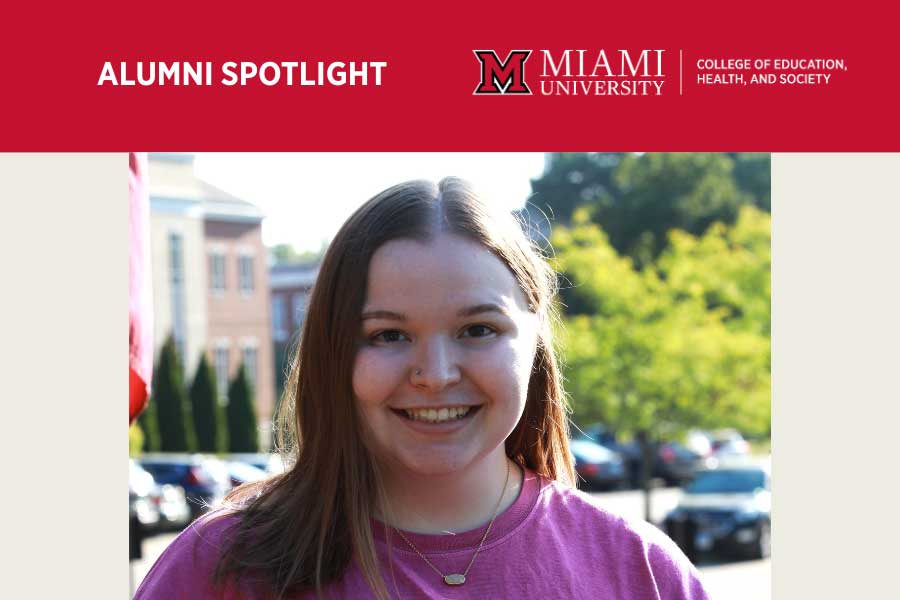 Leah Evans, a Miami University graduate, smiles while standing outdoors on campus with academic buildings and greenery behind her.