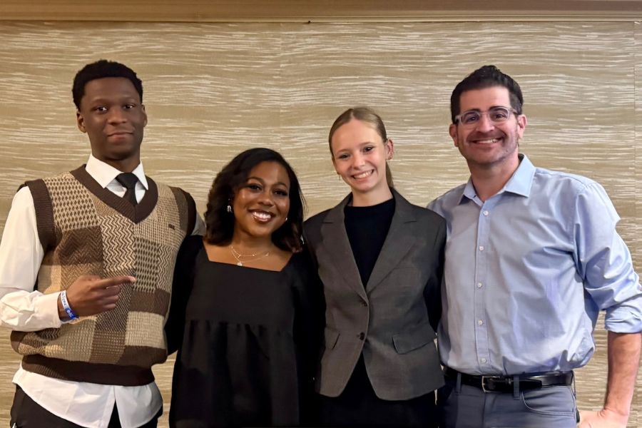 Toyon Embry, Sydnie Singleton, Giselle Pagliaro, and Brian Schultz posing together in a conference room.