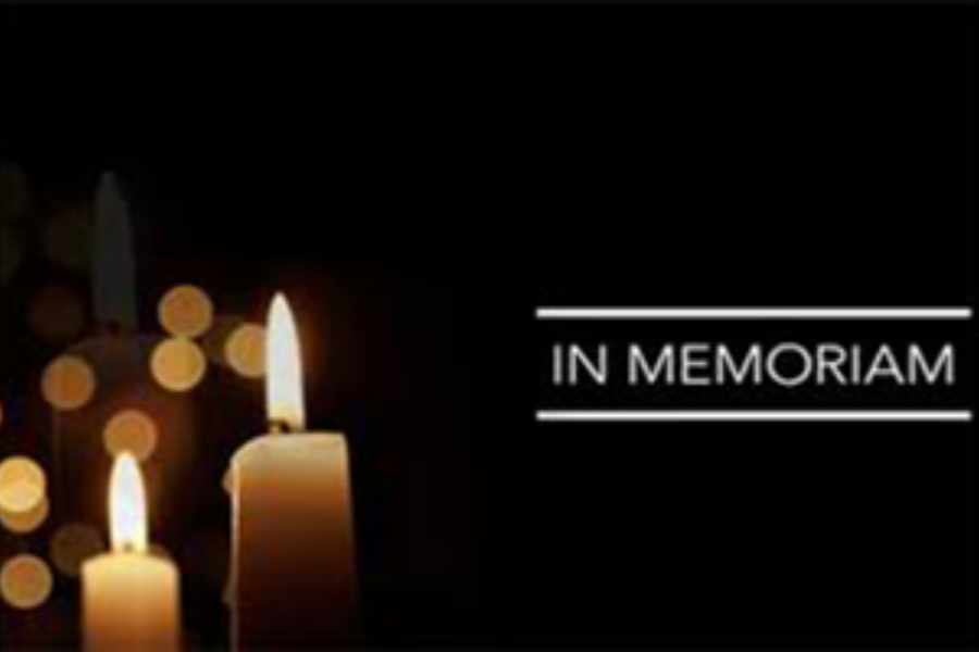 a lit candle next to the words in memoriam