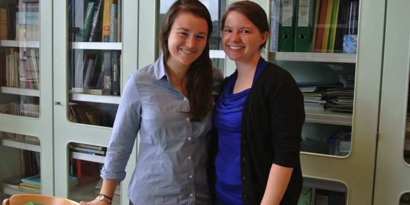 Student and cooperating teacher pose for a photo with a bookcase in the background.
