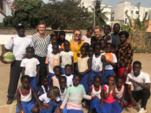 Students gather with children and adults from the Gambia for a photo.