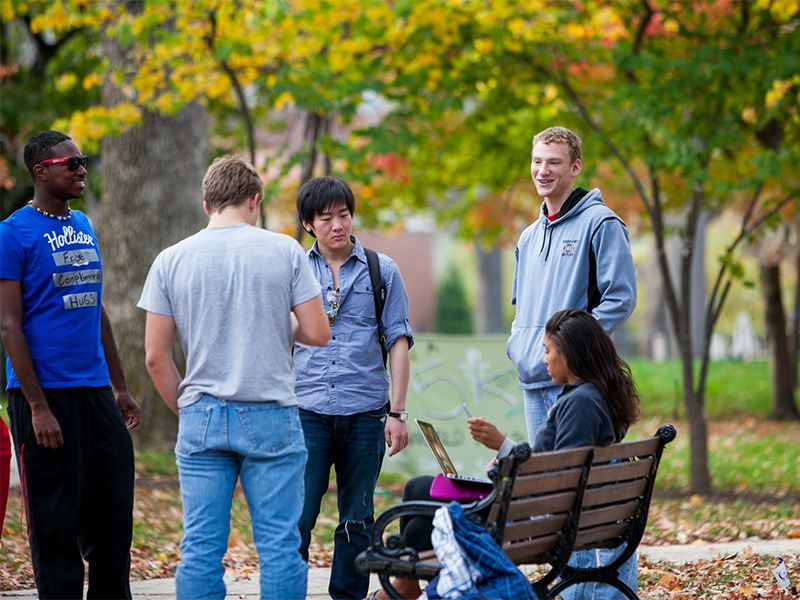 students chatting by a bench on campus