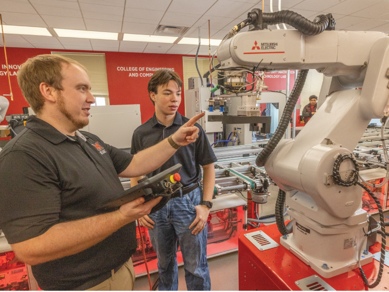 Engineering students using a robot in the Industrial Robotics Laboratory