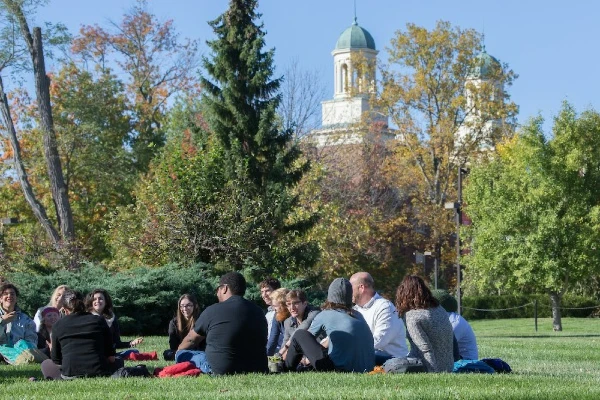 group of students in grass having a class discussion