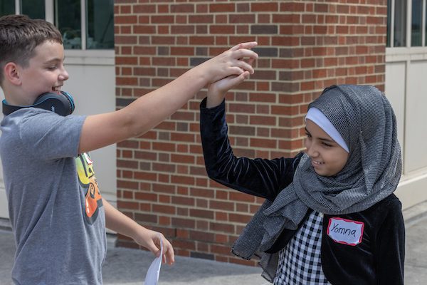 Students in a K-12 summer camp giving each other a high-five while working on a project.
