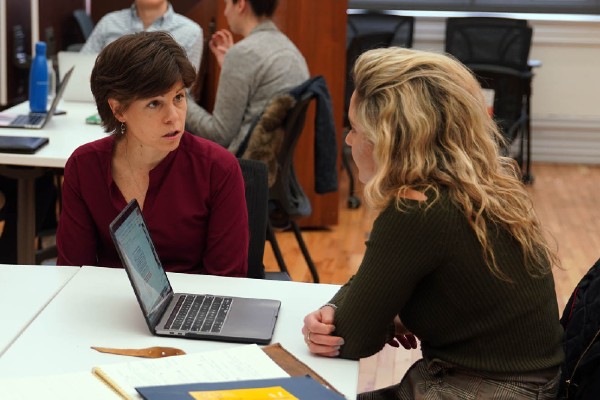 student working with professor in classroom