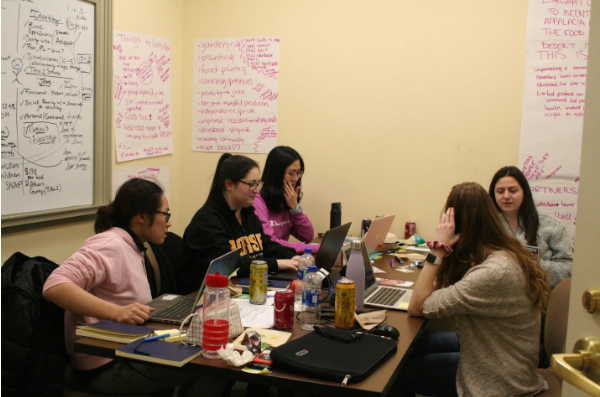 group of students working at table with laptops, drinks, and snack sitting on table