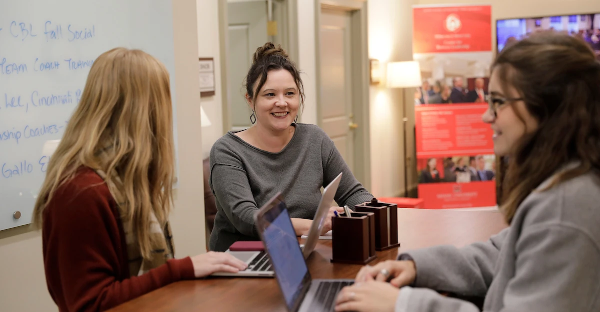 Megan Gerhardt speaking with students at a table