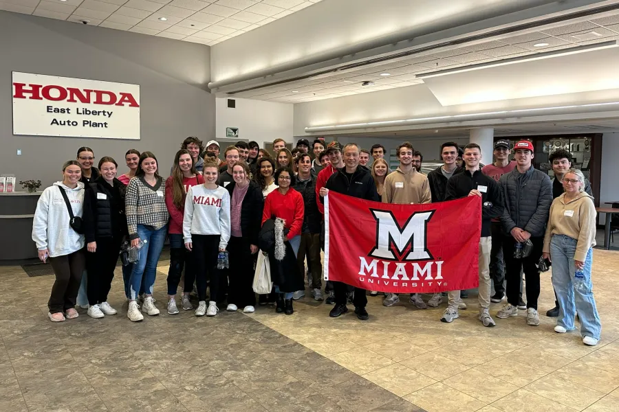 Farmer School students visit Honda, standing in lobby with Miami Flag