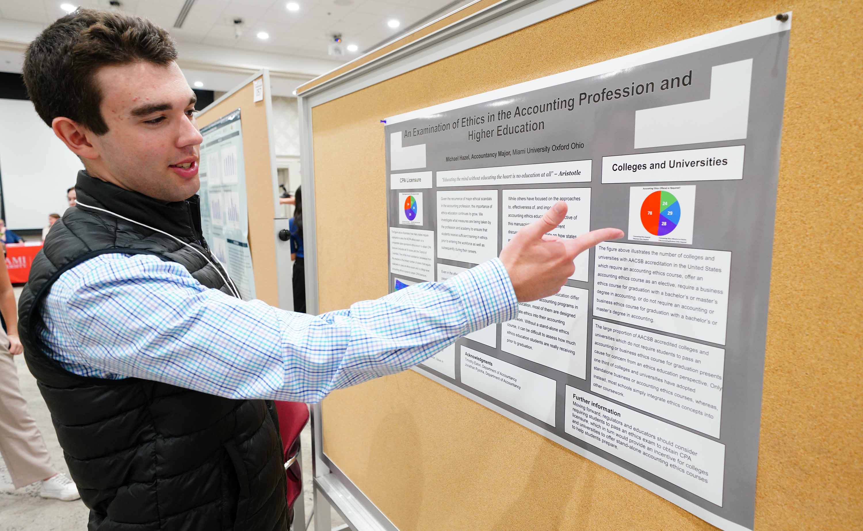 Student pointing out part of his research on his poster