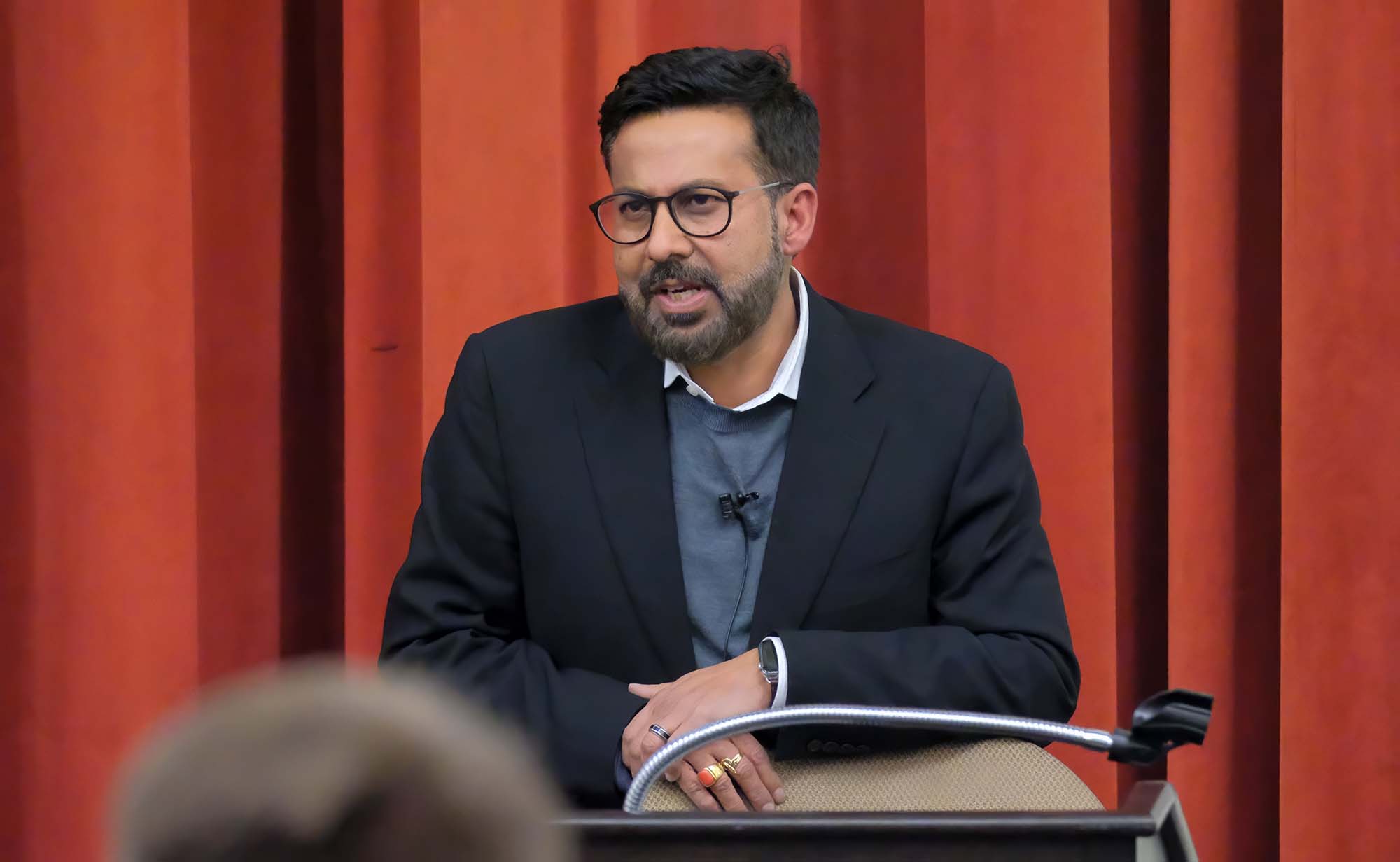 Raj talking to students in auditorium