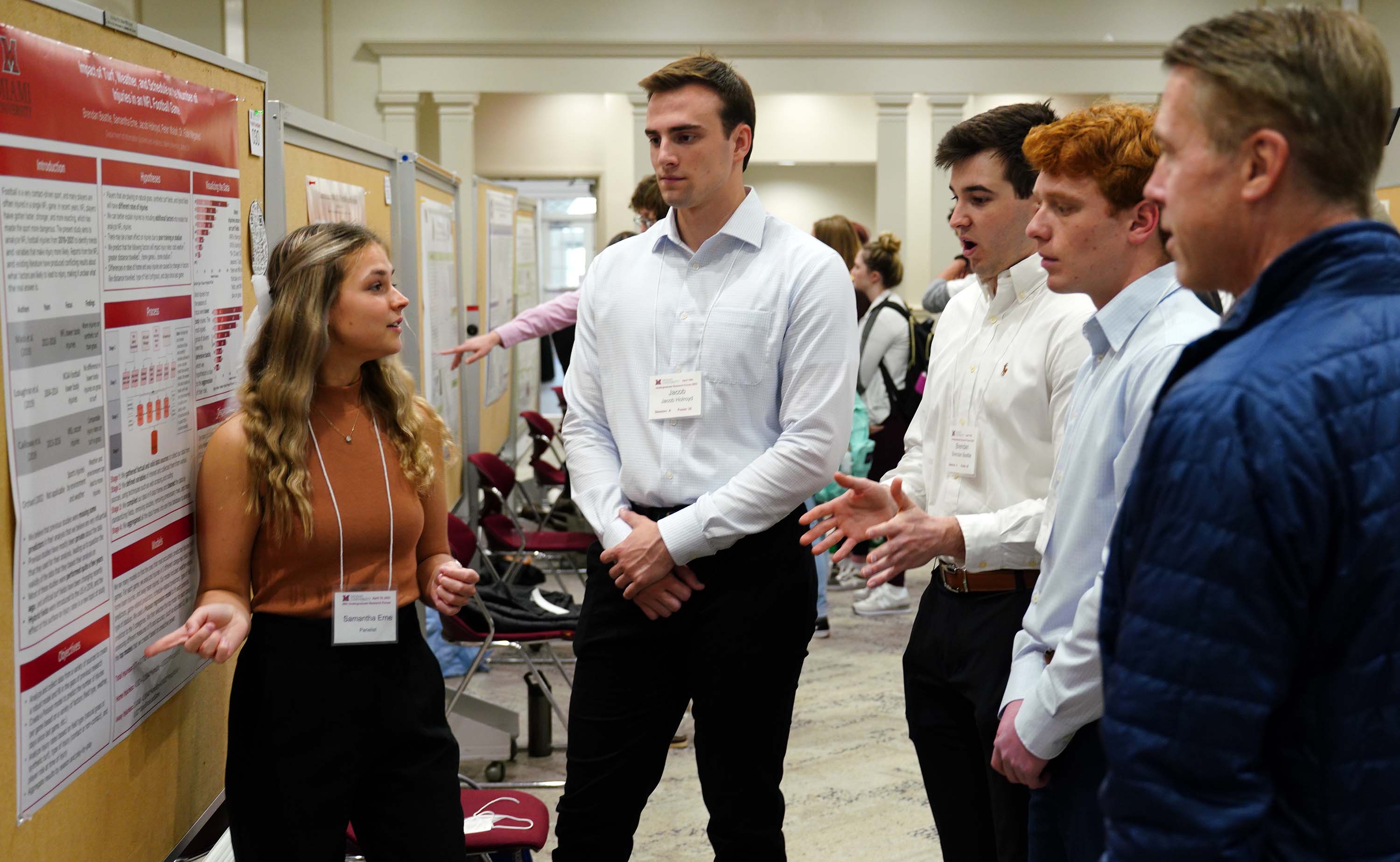 Students talk about research with visitor at forum