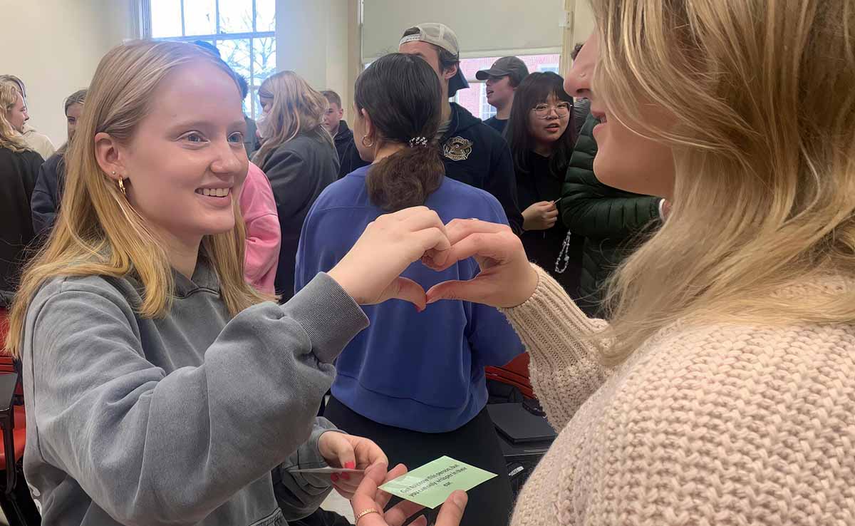 FYIC students in class make a heart with their hands