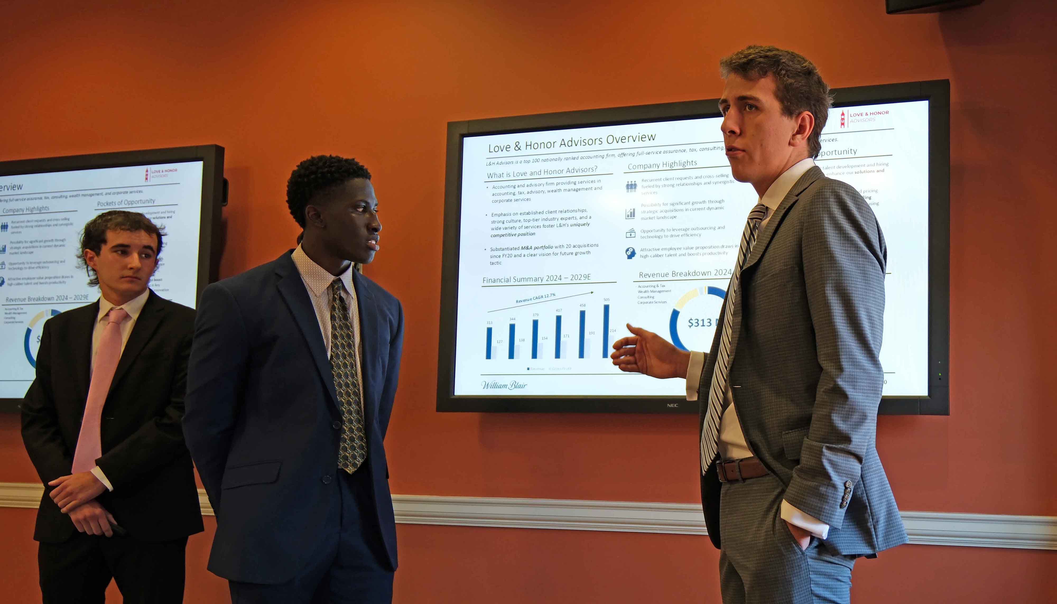 Two members of a team watch as third member makes presentation