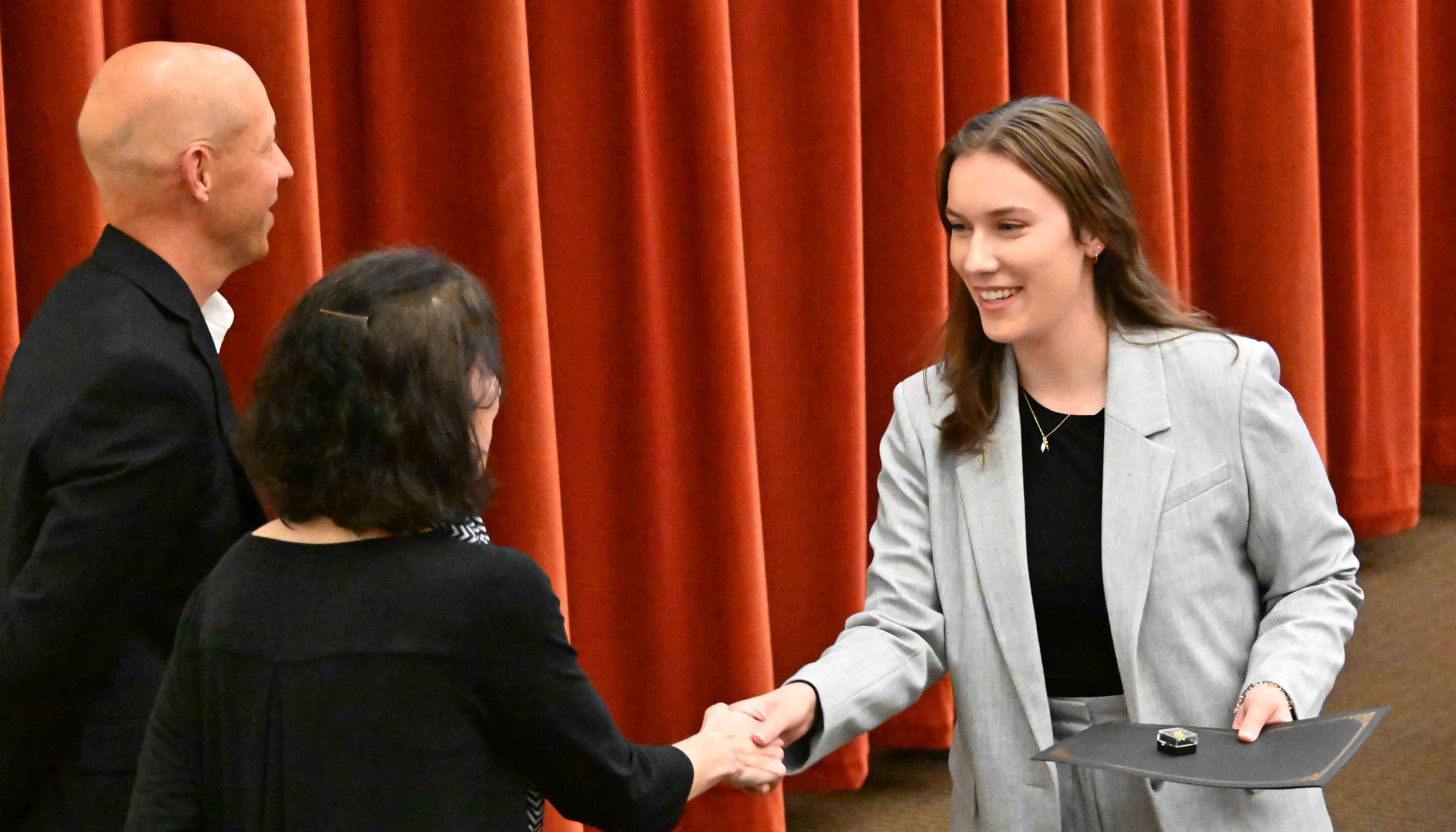 Student shakes hand with Michele Frank