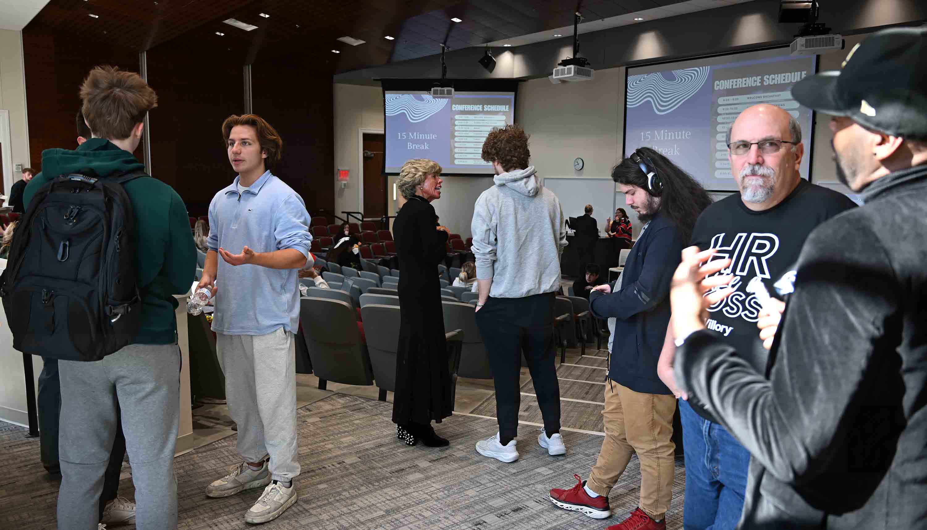 Students interacting during a conference break in an auditorium setting.
