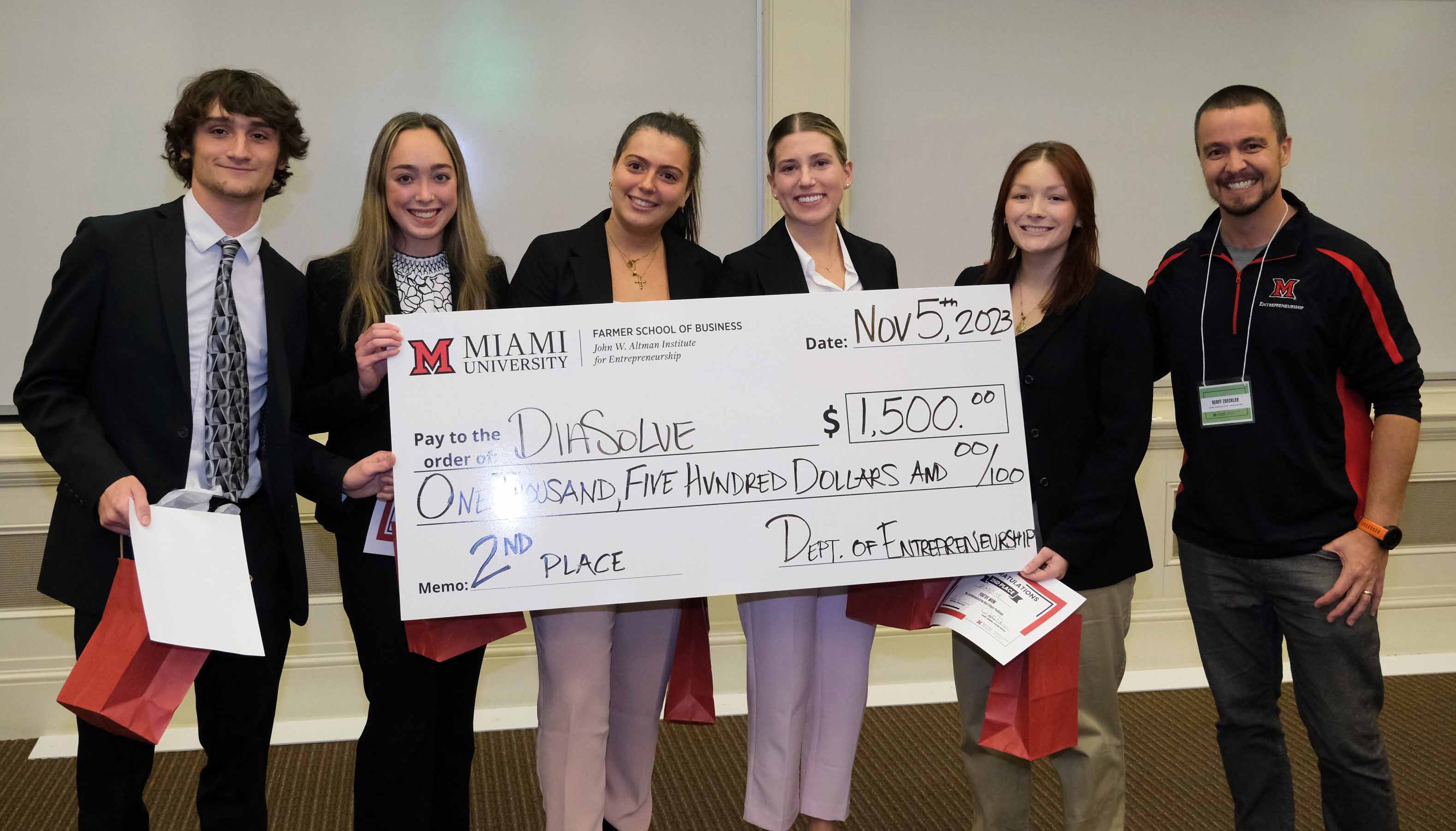 Amanda's team from Miami University's Farmer School of Business holding a large check for $1,500, awarded for second place in a competition on November 5, 2023.