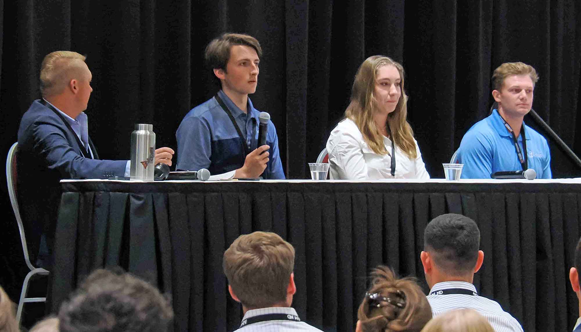 Panel discussion featuring four speakers engaged in conversation at a conference.