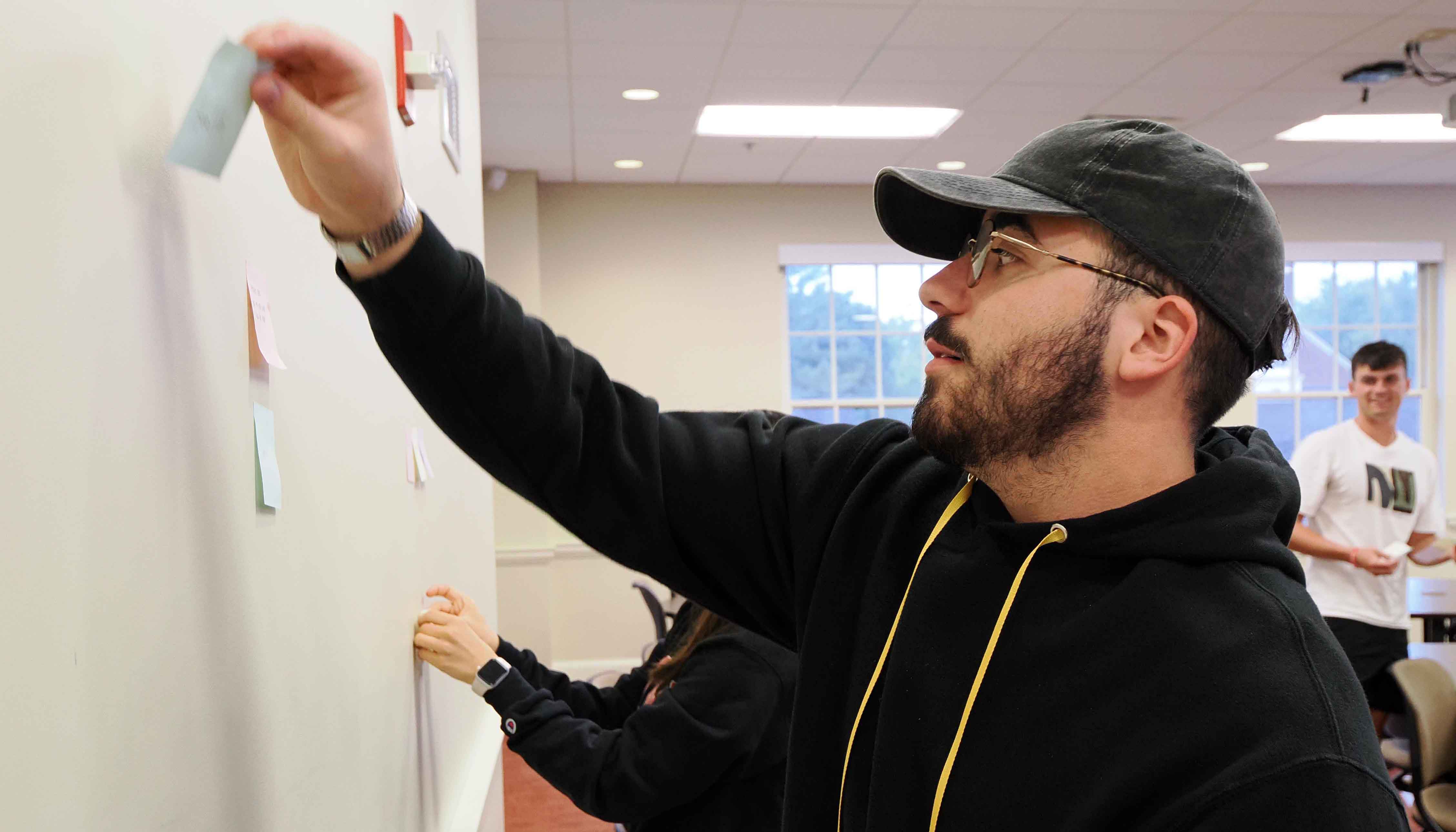 Student places post it note on a wall