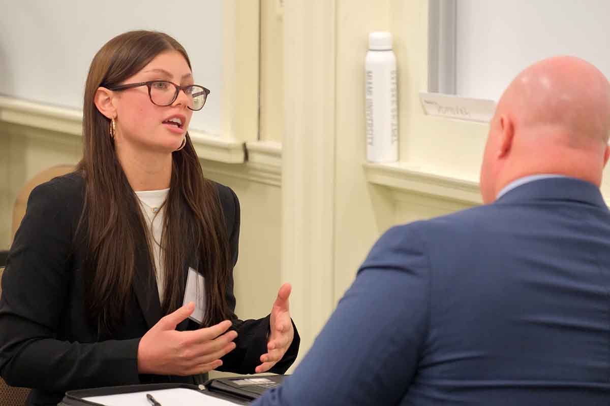 A woman in a black blazer engages in a conversation with a man during a professional networking event.