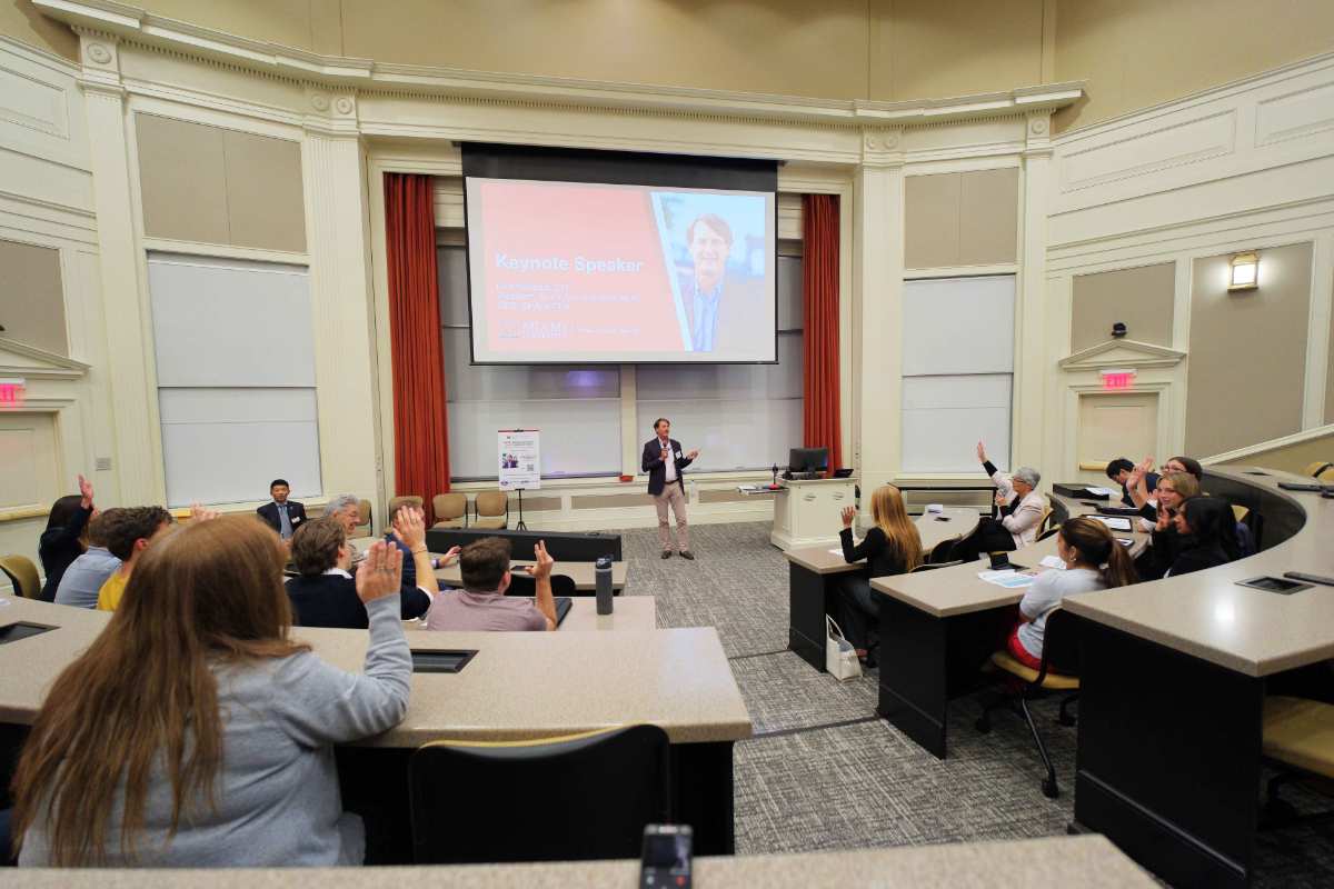 Audience participating during a keynote speaker event in a large lecture hall.