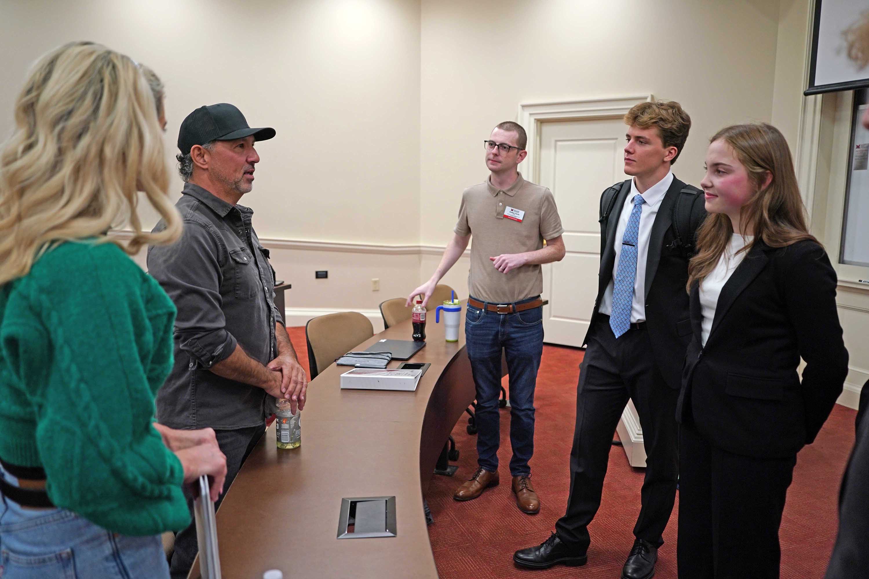 A group of students engaging in conversation with a guest speaker in a classroom setting.