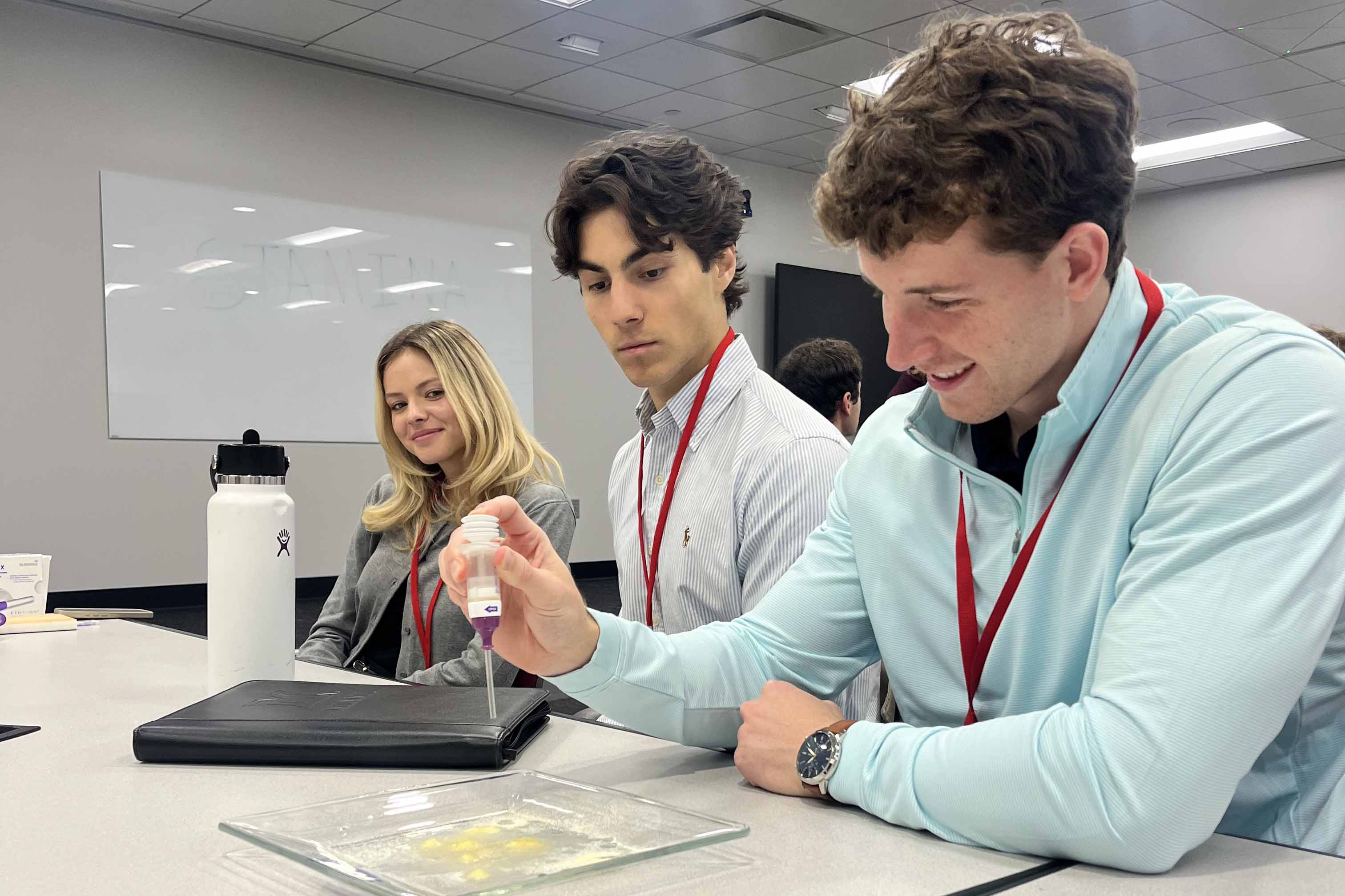 A student works with a piece of healthcare equipment while other students watch