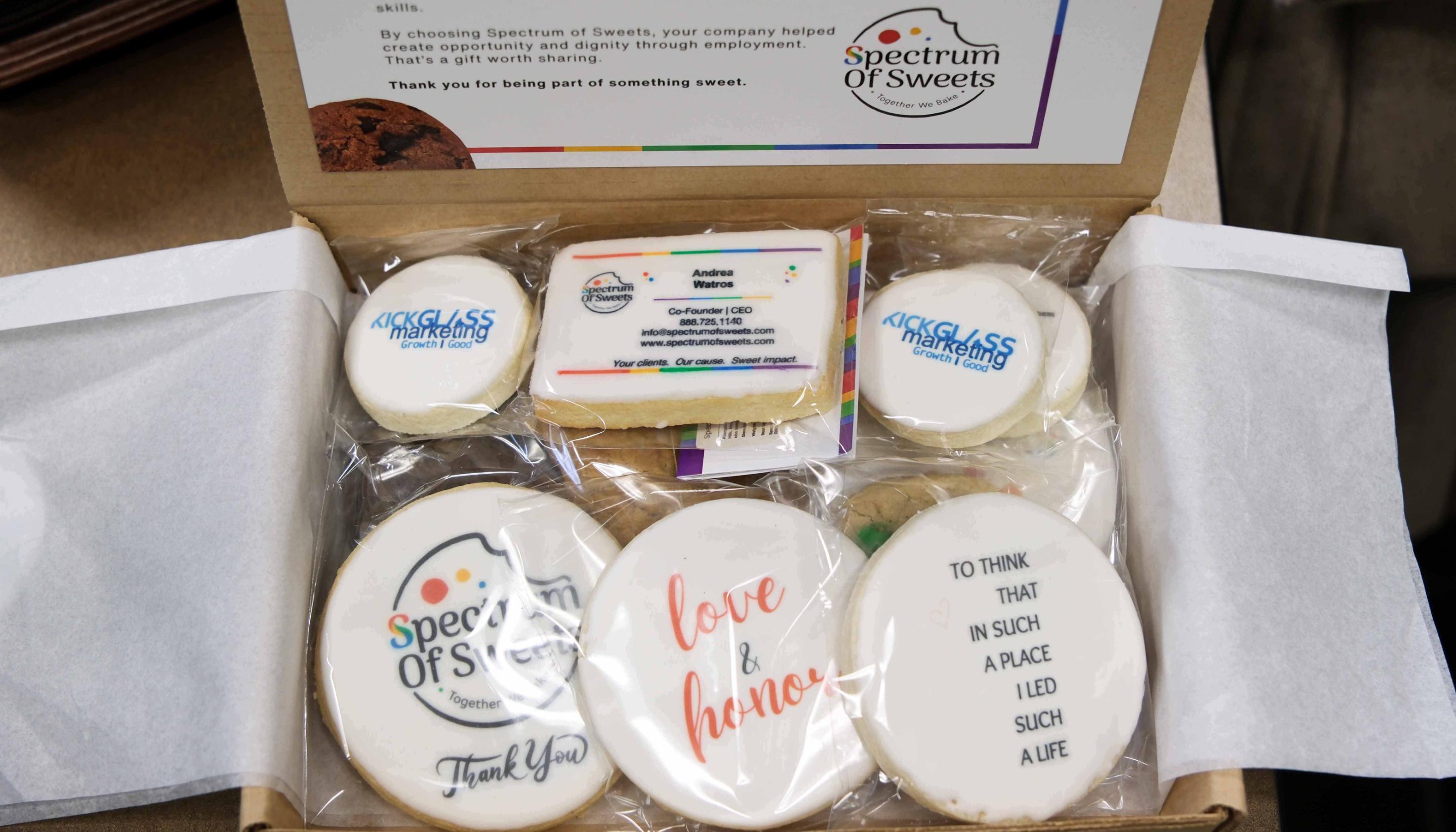 A selection of decorated cookies featuring the Spectrum of Sweets logo and messages of gratitude, presented in a gift box.