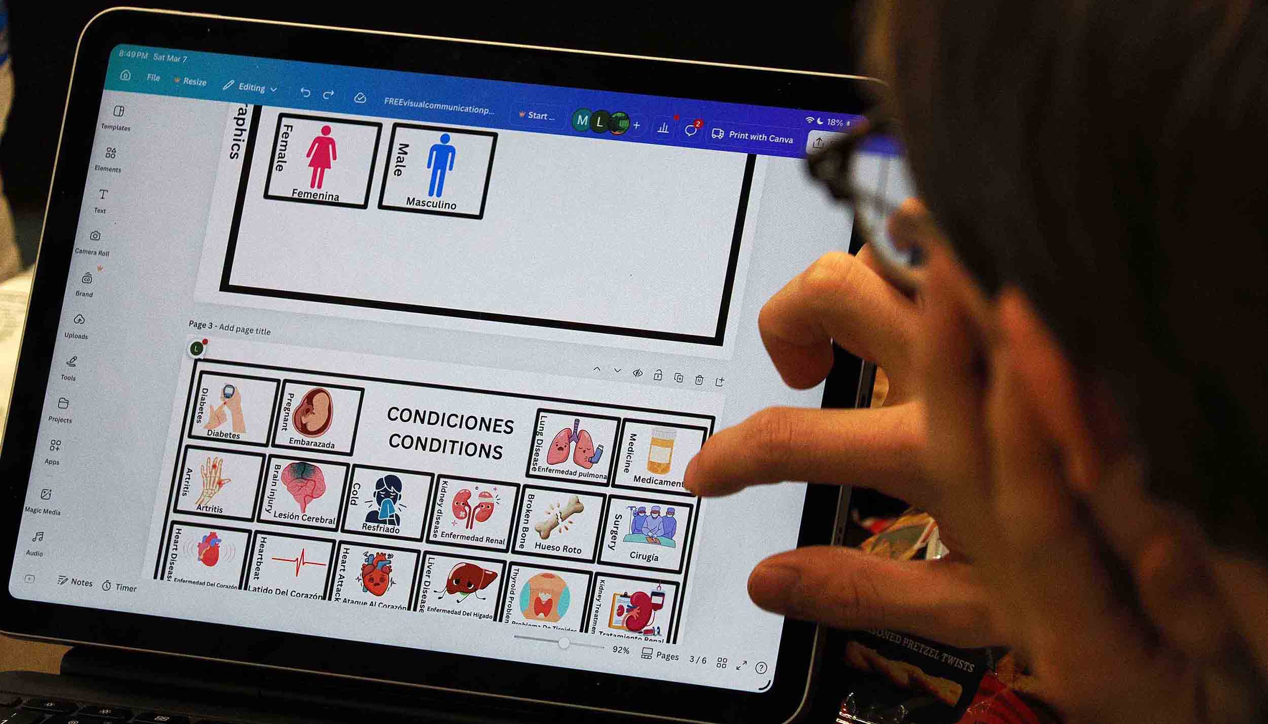 Person using a tablet to edit a bilingual communication board with health condition icons.