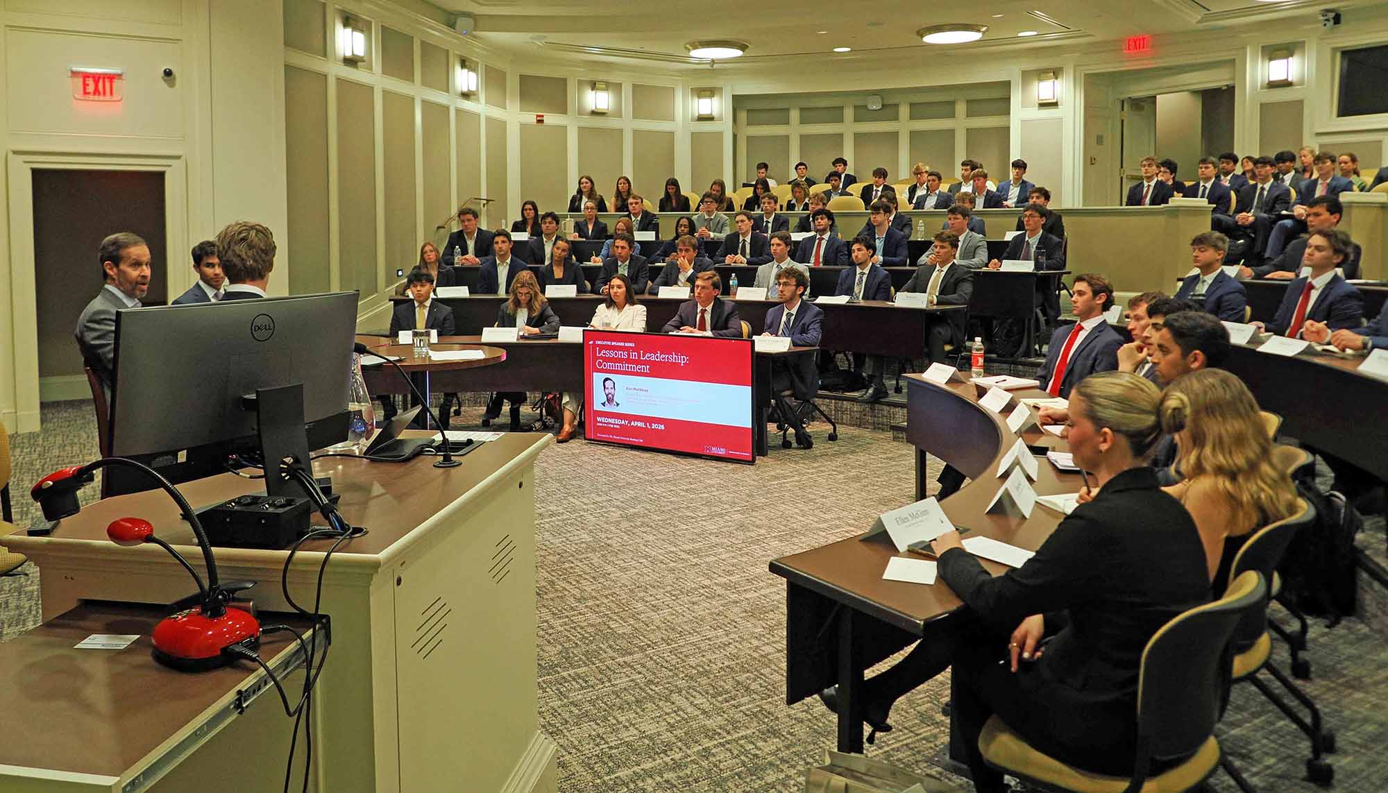 Speaker addresses a large group of students in a tiered lecture hall during a leadership presentation.