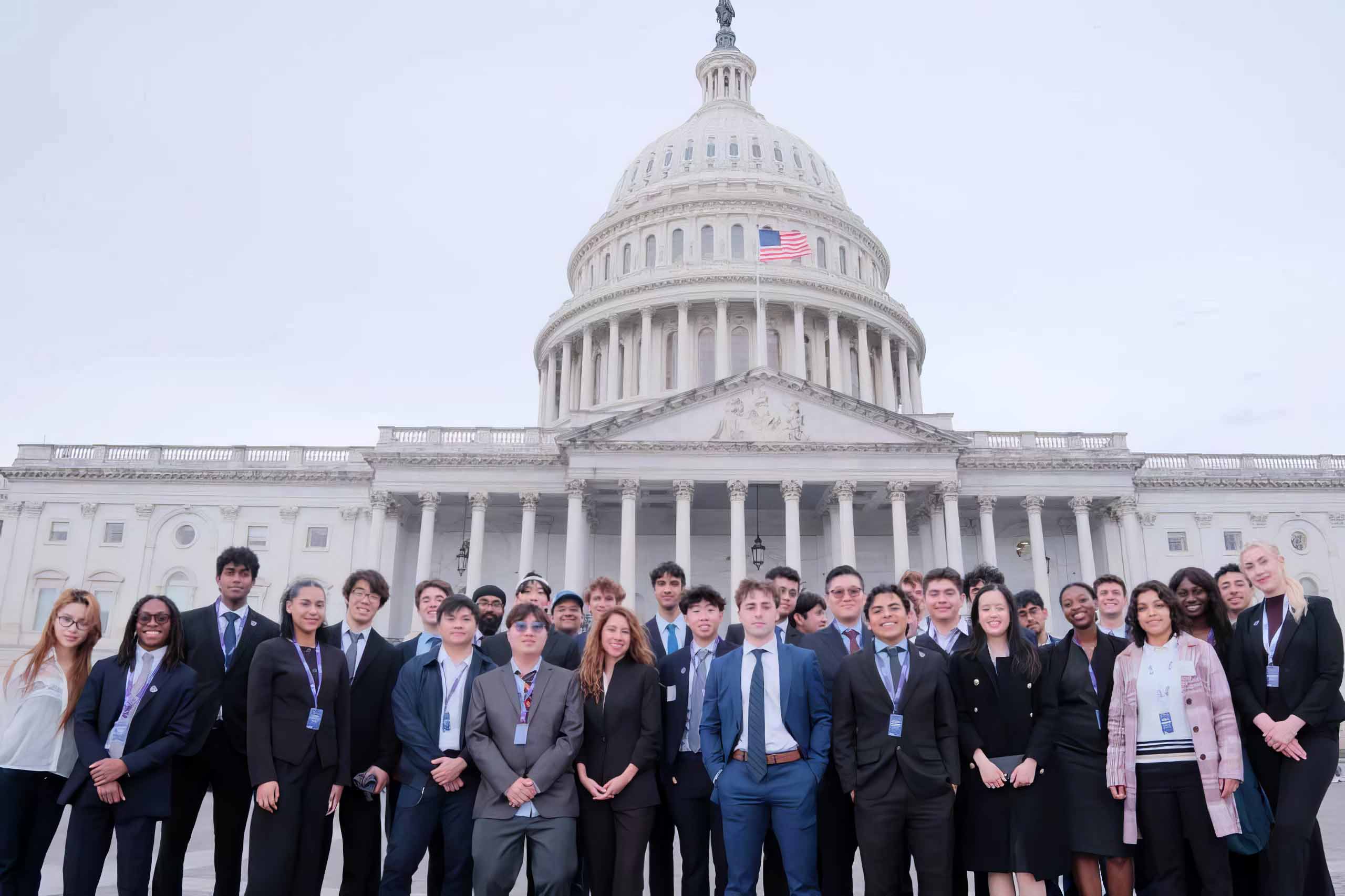 Group of students in business attire posing in front of the U.S. Capitol building.