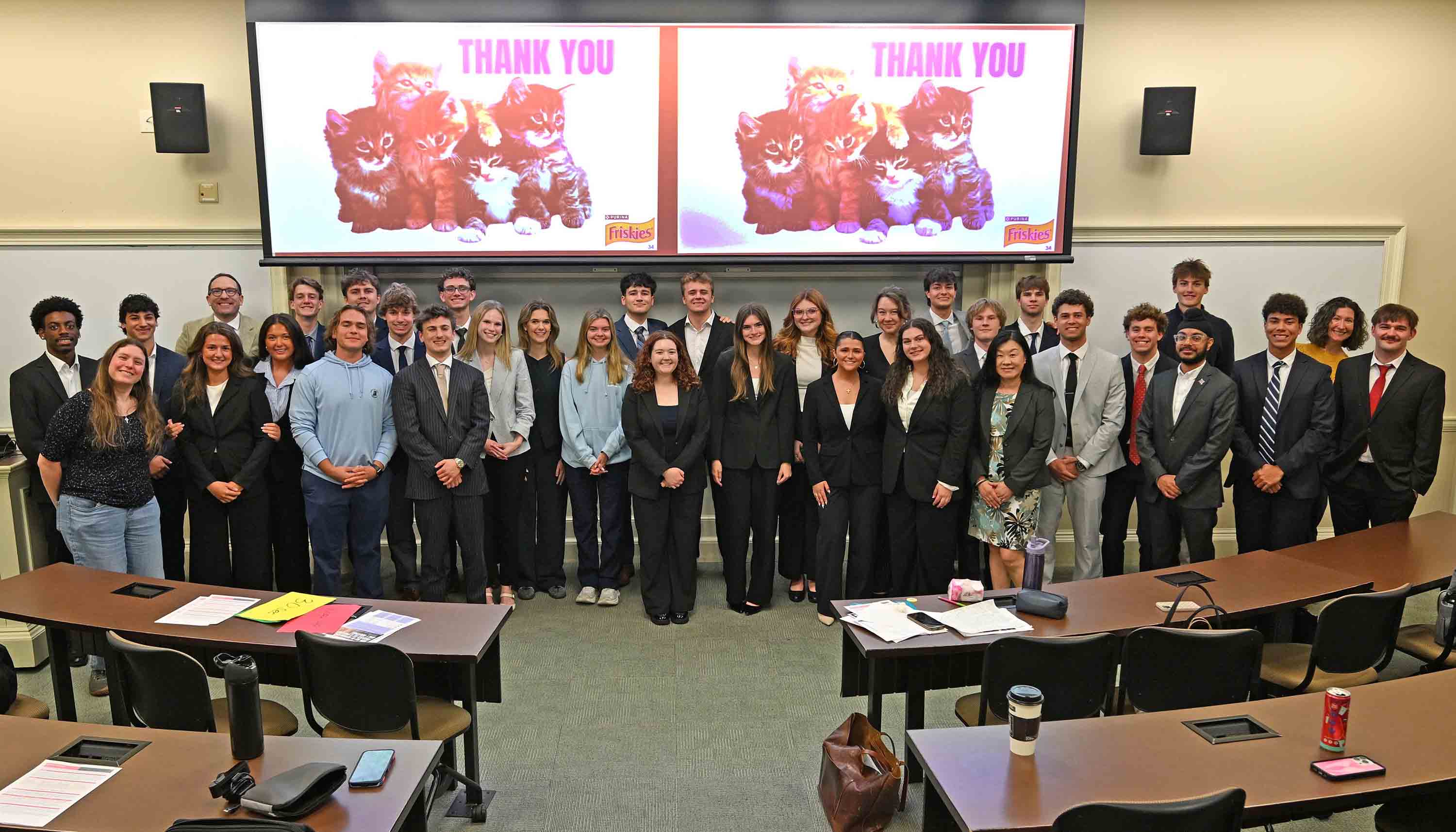 Large group posing in a classroom in front of a projection screen showing kittens with the words “THANK YOU.”