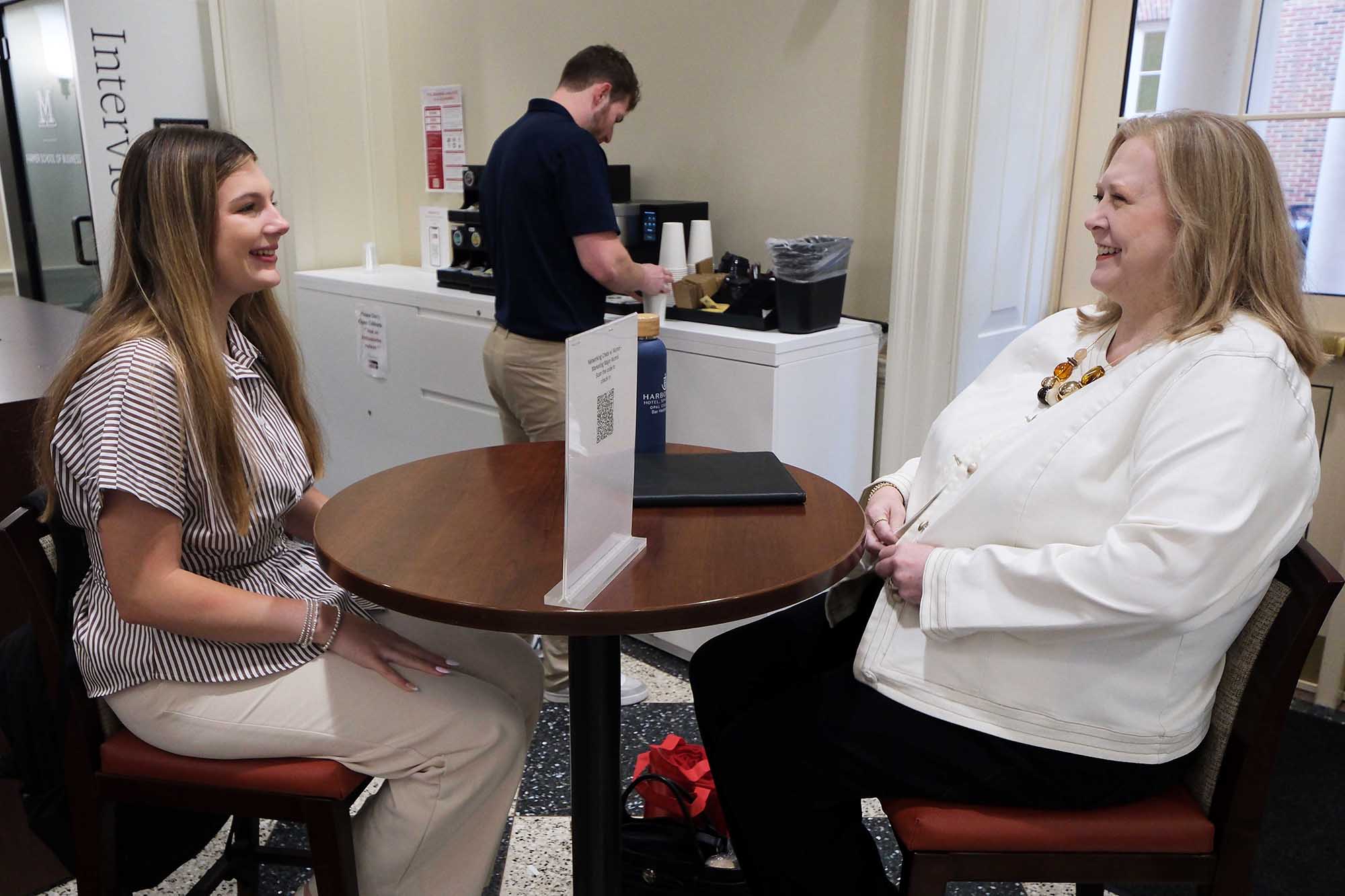 Student and alum talking at a table