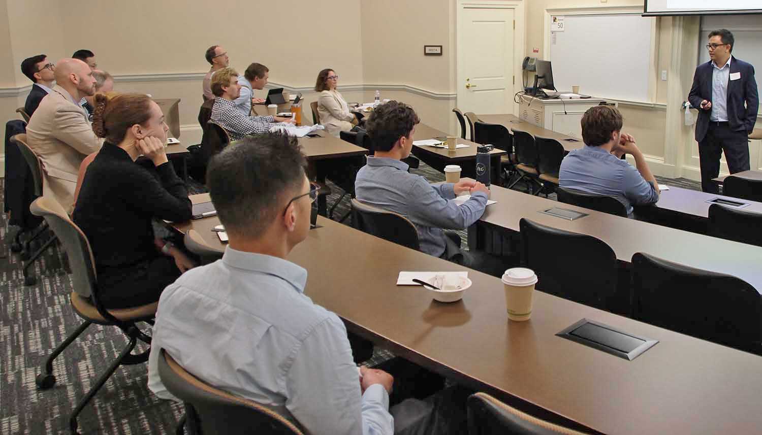 Man lecturing about his research to a group of finance faculty in the Farmer School of Business