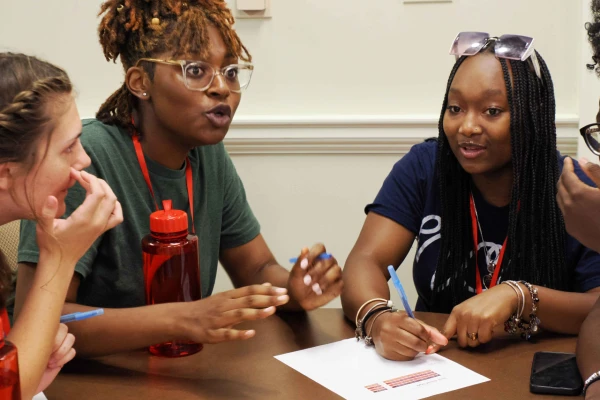 three female students at table discussing project