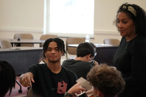 male student at table with female instructor talking to group