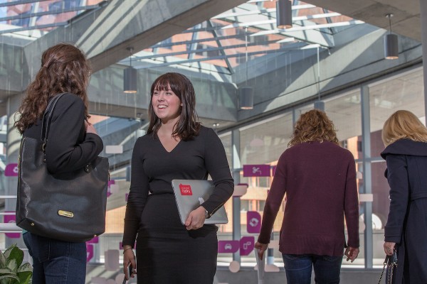 student holding a laptop talking to a recruiter in lobby