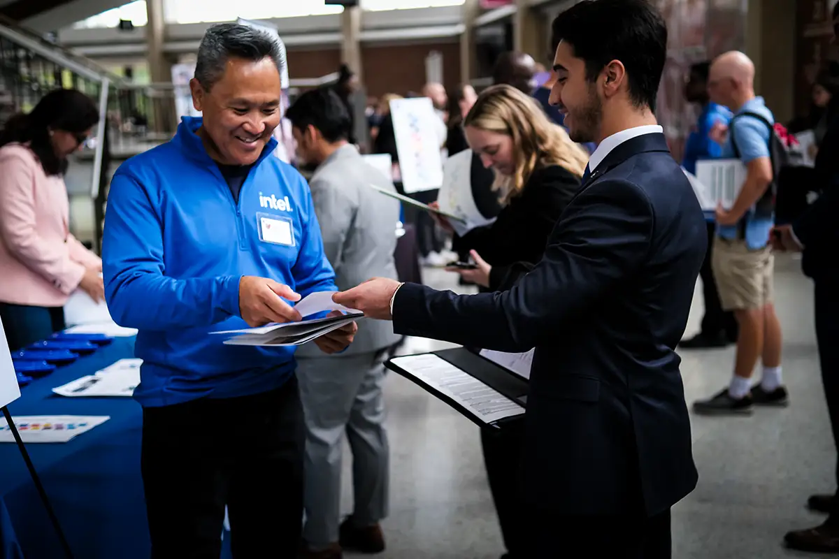 intel representative looking at resume with student at career fair