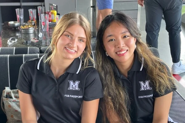 two female students at event wearing Miami University polo shirts